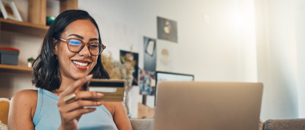 Woman on couch with laptop, credit card and online shopping, payment and ecommerce with fintech at home. Happy female customer at apartment, bank app and sale on store website with internet banking